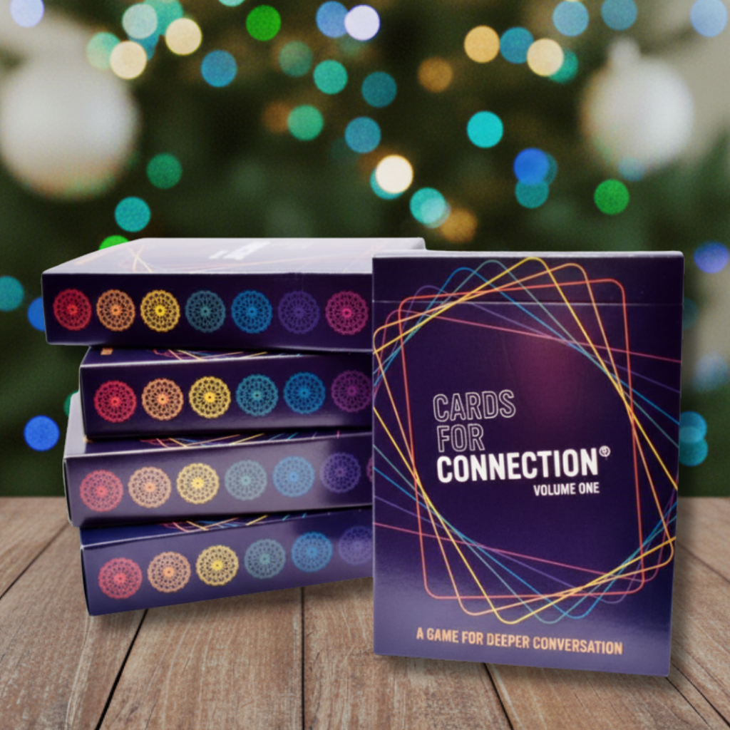 Five Cards for Connection game boxes on a wooden surface with a festive Christmas tree background