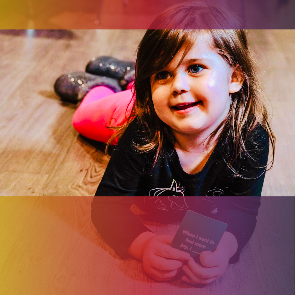 Child smiling and holding a Cards for Connection card while playing with family.