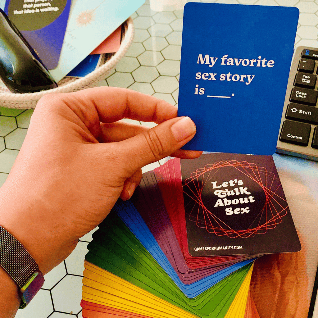 Hand holding a blue card with text, surrounded by other colorful cards on a table.