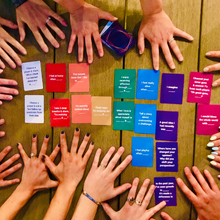 Load image into Gallery viewer, Multiple hands reaching toward Cards for Connection laid out neatly on a wooden table.