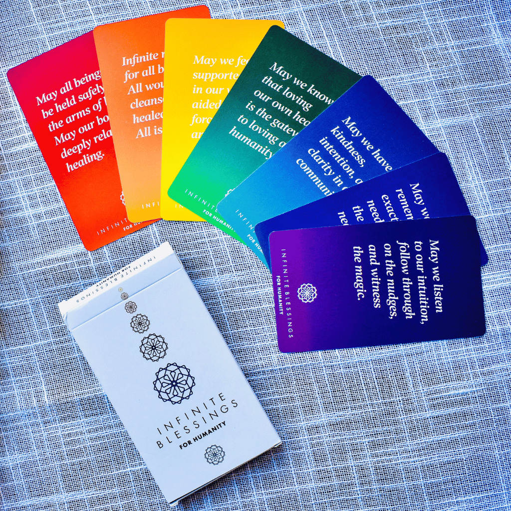 Infinite Blessings cards displayed in rainbow order on a textured blue fabric.