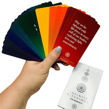 Load image into Gallery viewer, Hand holding a full rainbow fan of Infinite Blessings cards on a white background.