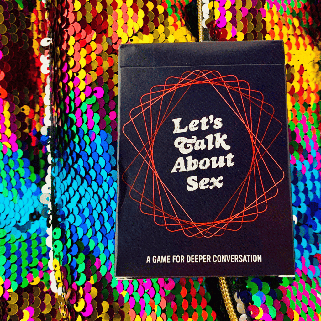 Let’s Talk About Sex deck box against a colorful sparkle sequin background.