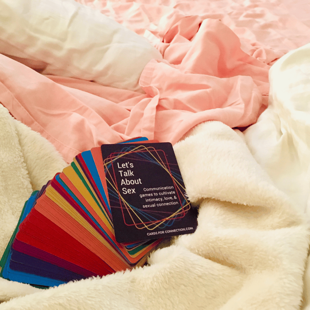 Colorful card deck titled 'Let's Talk About Sex' on a soft pink and beige blanket.