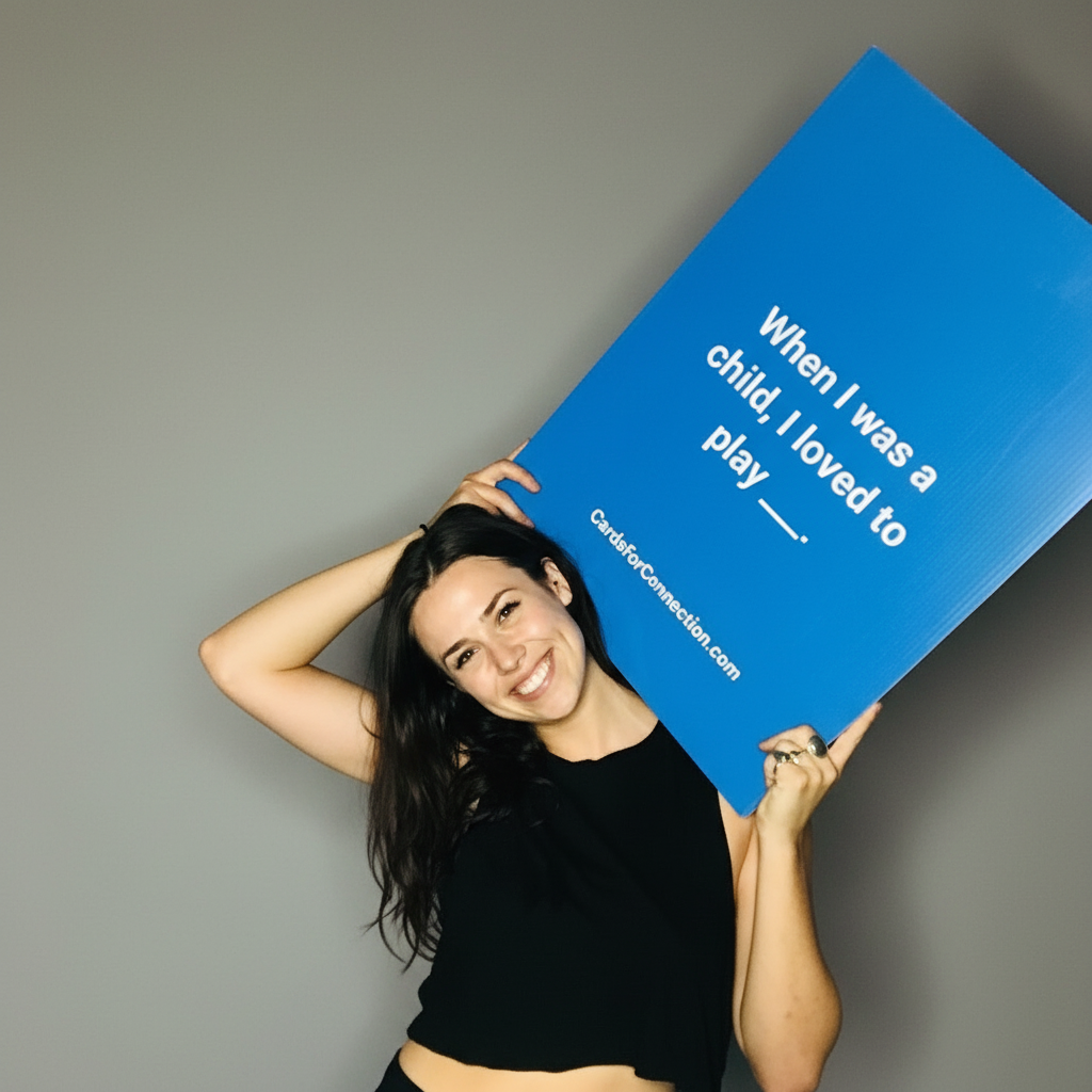 Woman holding a giant blue Cards for Connection sign with text against a gray background.